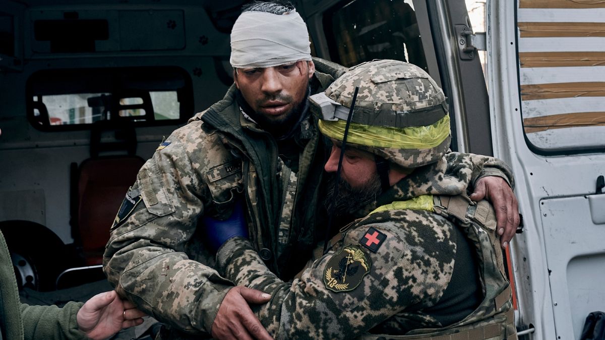 A Ukrainian soldier helps a wounded soldier at a hospital in Bakhmut, Donetsk region, Ukraine, Wednesday, Nov. 9, 2022.