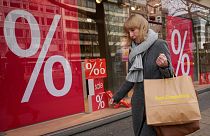 FILE - A woman walks with purchases past a store in Berlin, Friday, April 1, 2022.