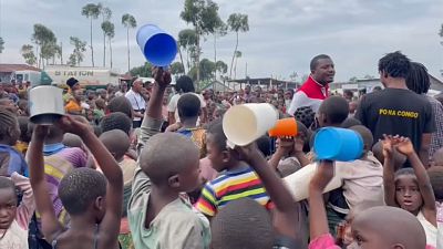 Children with plastic cups and containers waiting to receive food