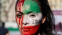 A woman is painted on a her face during a protest against the death of Mahsa Amini, a woman who died while in police custody in Iran, during a rally in central Rome