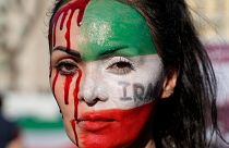A woman is painted on a her face during a protest against the death of Mahsa Amini, a woman who died while in police custody in Iran, during a rally in central Rome