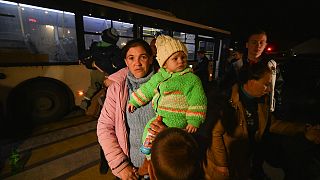 Evacuees from Kherson walk from a bus upon their arrival to Dzhankoi, Crimea, Thursday, Nov. 10, 2022.