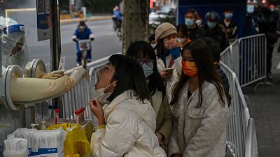 A health worker takes a swab sample from a woman to test for the Covid-19 coronavirus in the Jing'an district in Shanghai on December 7, 2022.