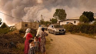 Moroccan women and children stand on a mountainous side road as wildfires sweep the region of Chefchaouen. Women are disproportionately impacted by climate change.
