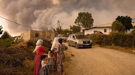 Moroccan women and children stand on a mountainous side road as wildfires sweep the region of Chefchaouen. Women are disproportionately impacted by climate change.