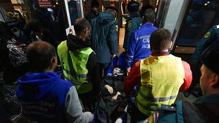 Volunteers and paramedics carry an elderly evacuee from Kherson into a hall on Nov. 10th 2022