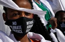 A girl wears a mask that reads "no climate justice without human rights" during a silent protest at COP27.