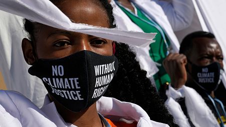 A girl wears a mask that reads "no climate justice without human rights" during a silent protest at COP27. 