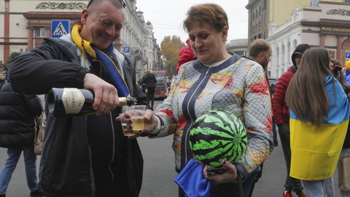 Eine Frau mit einer Wassermelone in der Hand und ein Mann feiern in der ukrainischen Stadt Odessa die Befreiung Chersons
