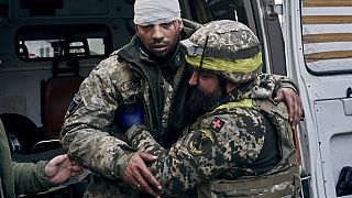 A Ukrainian soldier helps a wounded soldier at a hospital in Bakhmut, Donetsk region, Ukraine, Wednesday, Nov. 9, 2022.
