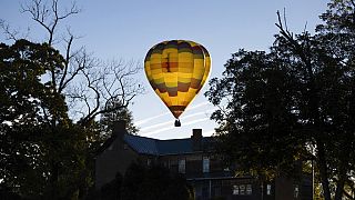 A hot air balloon drifts through the air between Chris Greene Lake and Panorama Farms in Charlottesville, Va., on Wednesday, Nov. 2, 2022.