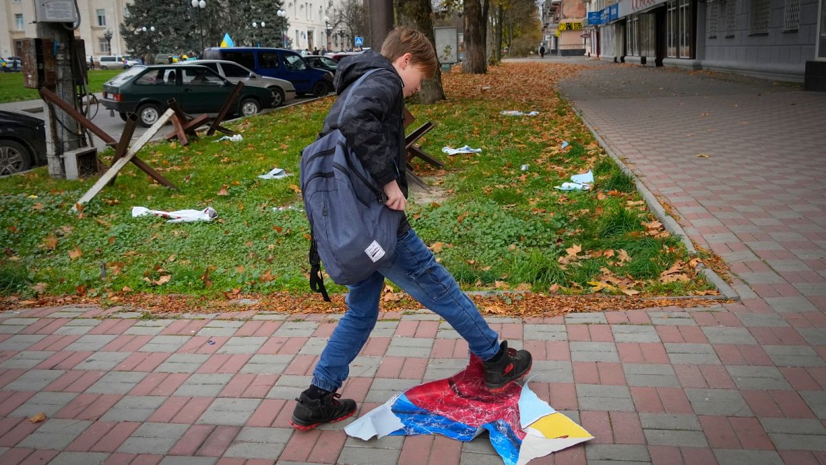 A boy tramples the Russian flag in central Kherson, Ukraine, Sunday, Nov. 13, 2022.