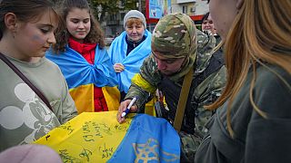 Ukrán katona ír alá egy zászlót Herszonban