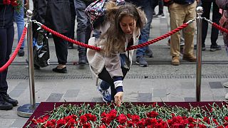 A woman leaves a flower at a memorial at the scene of Sunday's explosion on Istanbul's popular pedestrian Istiklal Avenue in Istanbul, Monday, Nov. 14, 2022.