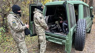 Two officers from Ukraine's security services quiz a man accused of colloborating with the Russians in the Kharkiv region