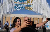 Two people take selfies at the COP27 UN Climate Summit.