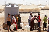 Fiatal szíriai menekültek töltik meg víztartályaikat a zaatari menekülttáborban, Jordániában, 2013-ban