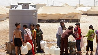 Fiatal szíriai menekültek töltik meg víztartályaikat a zaatari menekülttáborban, Jordániában, 2013-ban