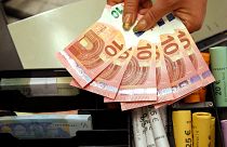 Euro coins and banknotes are shown by a salesclerk at a shop in Vilnius, Lithuania.