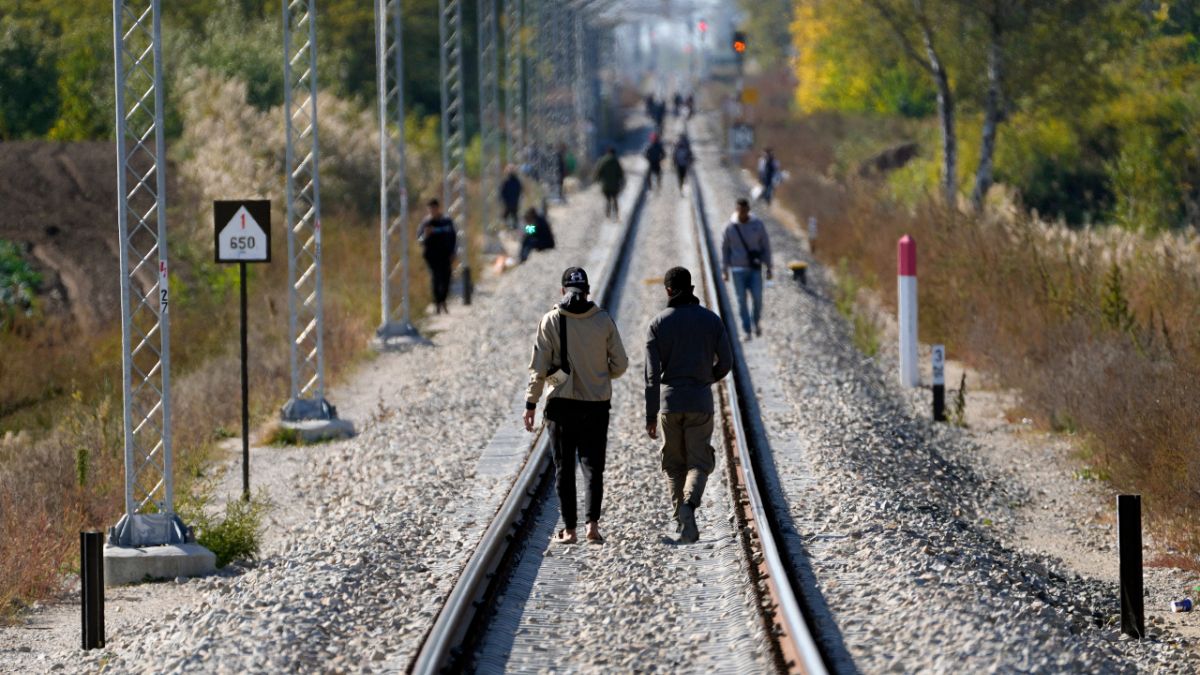 مهاجرون يسيرون فوق خطوط السكك الحديدية بالقرب من خط الحدود الفاصل بين صربيا والمجر، بالقرب من قرية هورجوس، صربيا، 20 أكتوبر 2022