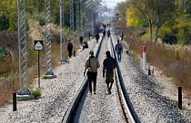 مهاجرون يسيرون فوق خطوط السكك الحديدية بالقرب من خط الحدود الفاصل بين صربيا والمجر، بالقرب من قرية هورجوس، صربيا، 20 أكتوبر 2022