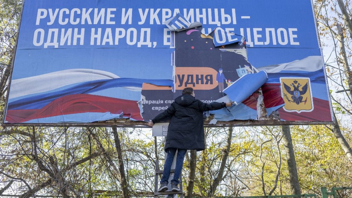 Un habitant de Kherson retire une affiche russe - le 14/11/2022