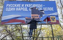 Un habitant de Kherson retire une affiche russe - le 14/11/2022