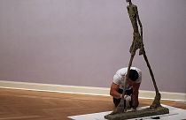 A sculpture "L'Homme qui marche" (2ndR) by Swiss artist Alberto Giacometti is prepared by an employee of the Pablo Picasso Museum in Muenster