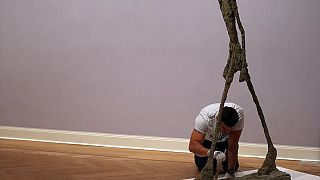 A sculpture "L'Homme qui marche" (2ndR) by Swiss artist Alberto Giacometti is prepared by an employee of the Pablo Picasso Museum in Muenster