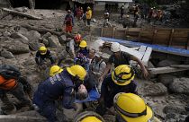 Trabajadores de emergencia llevan a una mujer rescatada de una zona inundada por un río que se desbordó. El 18 de octubre de 2022.