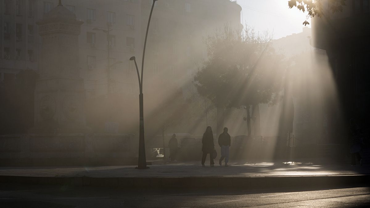 People walk in the street amid dense fog at morning at Terazije square in downtown Belgrade, Serbia, Wednesday, Nov. 9, 2022.