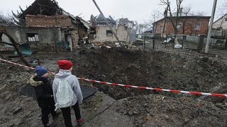 Duas crianças olham para destroços dos bombardeamentos russos em Lviv, Ucrânia