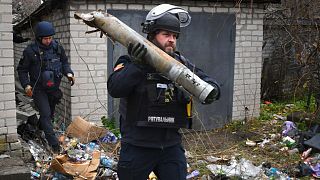 A Ukrainian sapper carries a part of a projectile during a demining operation in a residential area in Lyman, Donetsk region, Ukraine, Wednesday, Nov. 16, 2022.