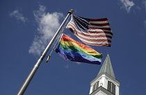 A gay pride rainbow flag flies with the U.S. flag in front of the Asbury United Methodist Church in Prairie Village, Kansas, on Friday, April 19, 2019.