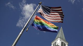 A gay pride rainbow flag flies with the U.S. flag in front of the Asbury United Methodist Church in Prairie Village, Kansas, on Friday, April 19, 2019.