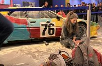 ناشطة بيئية من حركة "الجيل الأخير" بجانب السيارة وهي من نوع "بي ام دبليو ام 1" طراز 1979، معروضة في مركز فابريكا ديل فابوره الثقافي، ميلانو إيطاليا.