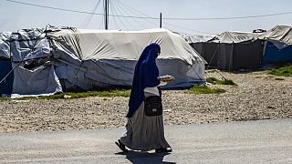 A woman walks through Camp Roj, where relatives of suspected IS supporters are held.