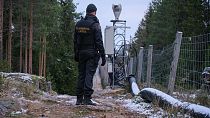 Finnish border guard patrolling fence with Russia