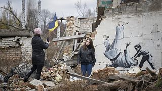 Des personnes se prennent en photo devant une oeuvre de Banksy, à Borodyanka, Ukraine, le 13 novembre 2022