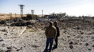 Habitantes de Taql Baql, Síria, olham para destroços na central elétrica local, após ataques aéreos da Turquia