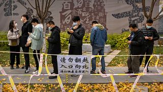 People wearing face masks stand in line for COVID-19 tests at a coronavirus testing site in Beijing, Saturday, Nov. 19, 2022.