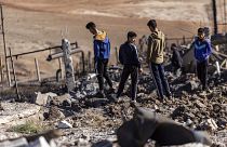 People inspect a site damaged by Turkish airstrikes that hit an electricity station in the village of Taql Baql, Syria.