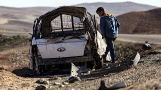 A man inspects a damaged car that was hit by Turkish airstrikes near an electricity station in the village of Taql Baql, in the Hasakeh province, Syria.
