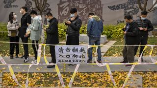 أشخاص يقفون في طابور لإجراء اختبارات COVID-19 في موقع اختبار فيروس كورونا في بكين.