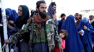 یک نیروی طالبان در میان مردم که منتظر دریافت جیره غذایی خود در کابل افغانستان هستند