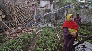 A woman walks past a house damaged by an earthquake in Cianjur, West Java, Indonesia, Monday, Nov. 21, 2022.