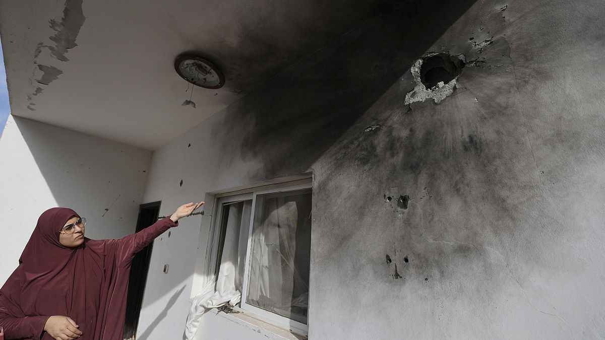 امرأة فلسطينية تشير إلى ثقوب على جدار ناجمة عن اقتحام الجيش الإسرائيلي للمنزل 