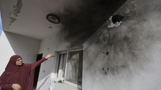 امرأة فلسطينية تشير إلى ثقوب على جدار ناجمة عن اقتحام الجيش الإسرائيلي للمنزل
