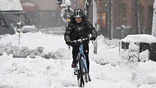 الصورة لمواطن يتنقل بواسطة دراجة هوائية وسط الثلوج في السويد 
