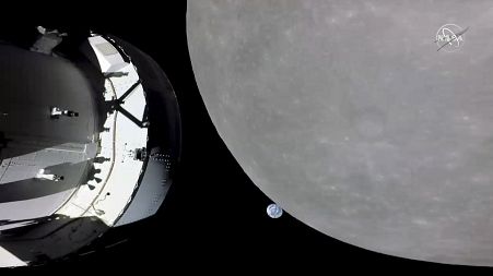This screengrab from NASA TV shows NASA's Orion capsule, left, nearing the moon, right, Monday, Nov. 21, 2022. At center is earth.